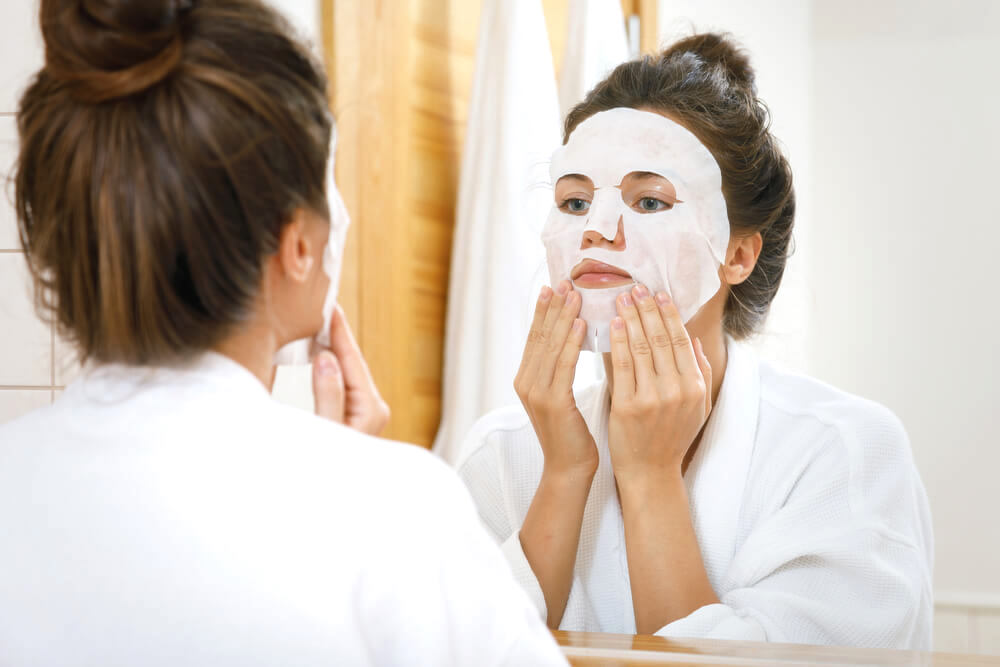 woman applying sheet mask