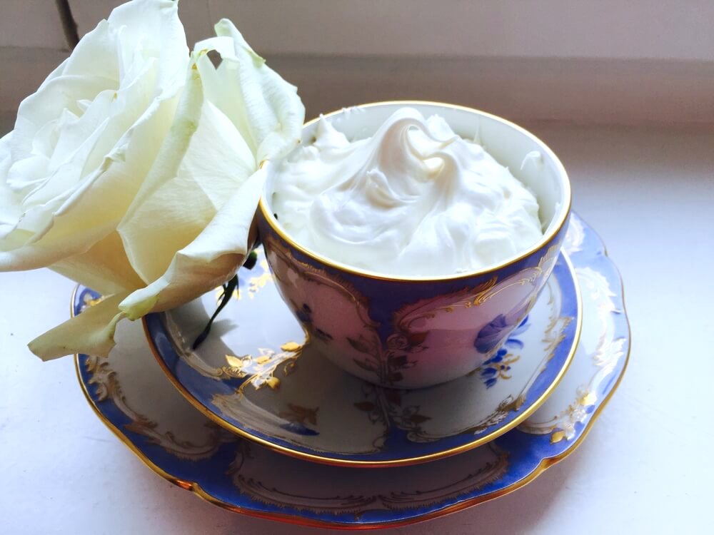 DIY body butter in a bowl with a white rose