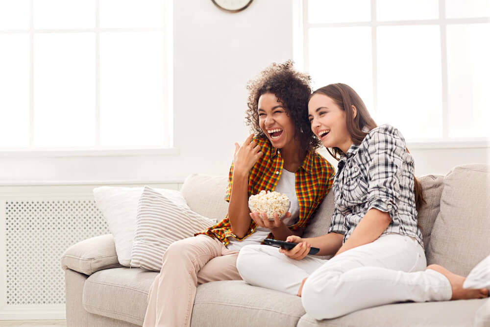 Two female friends enjoying watching film at home