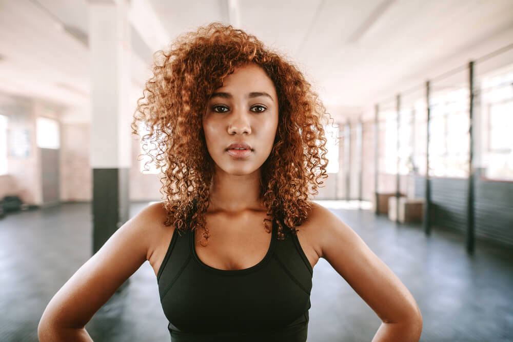 Woman with thick curly hair standing in a gym