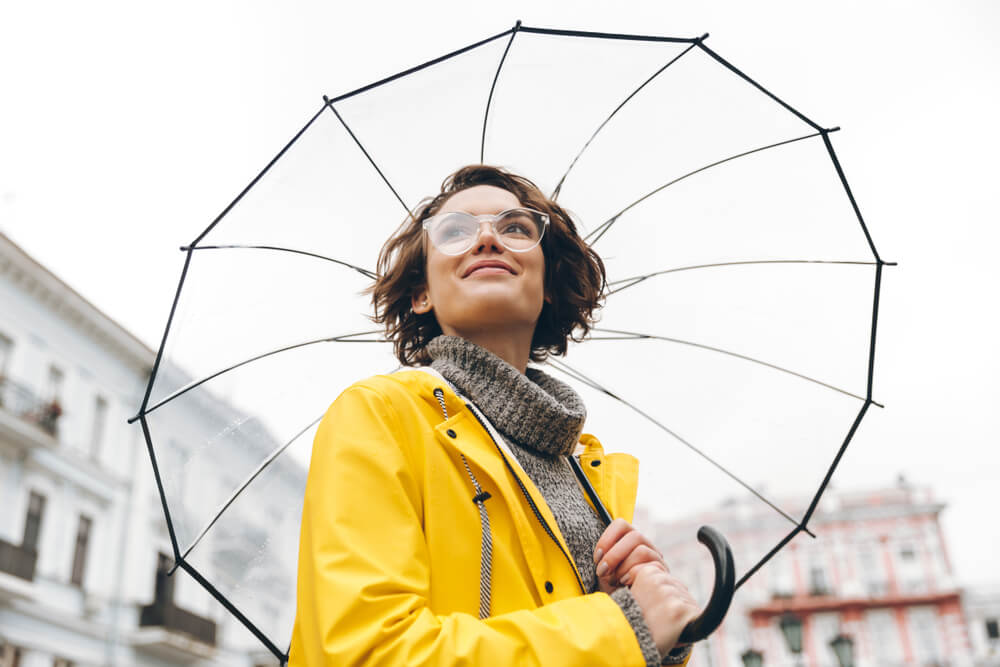 Woman in yellow raincoat holding a transparent umbrella 