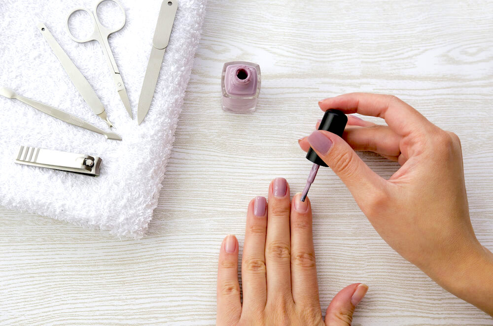 Applying nail polish, surrounded by nail care