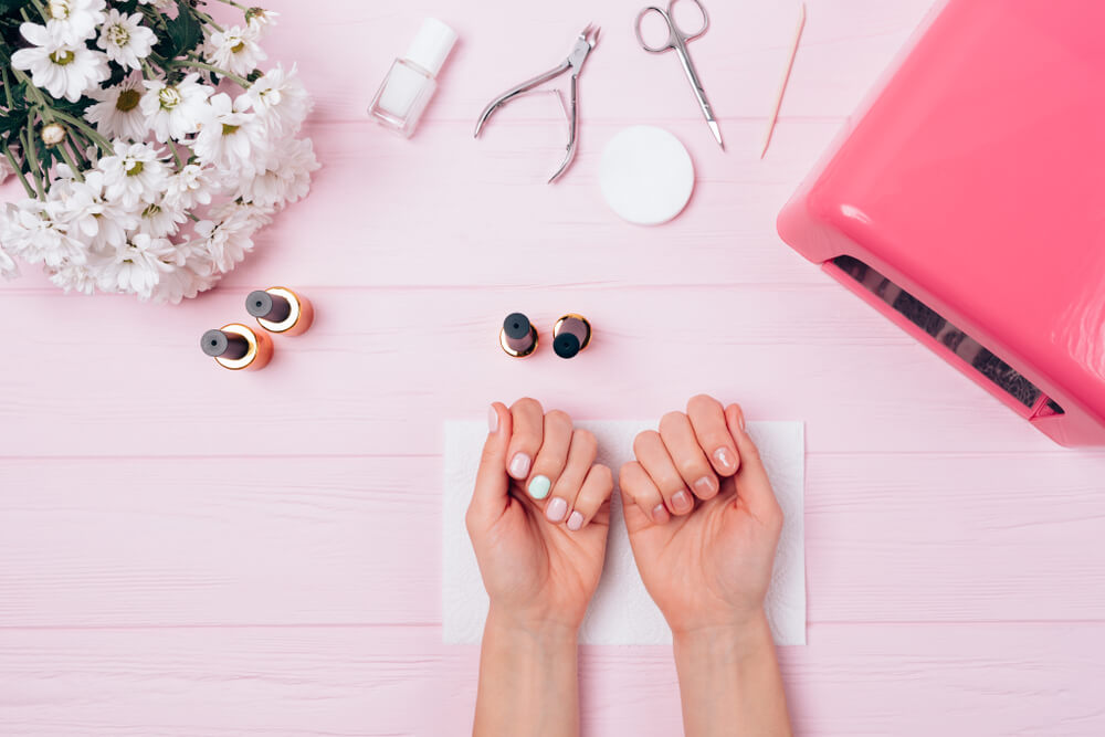 Manicured nails surrounded by flowers and nail care