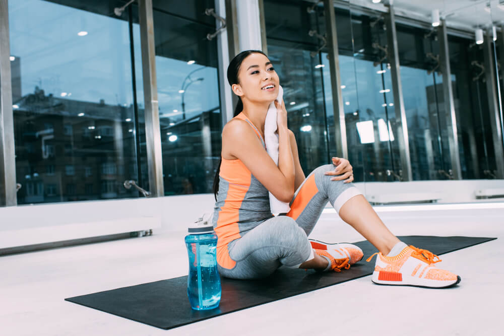 Woman wiping face with a towel at the gym 