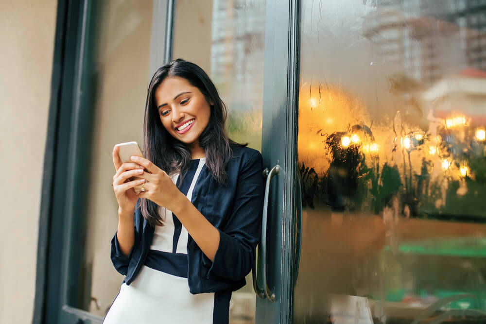 Smiling woman using her phone outside a cafe