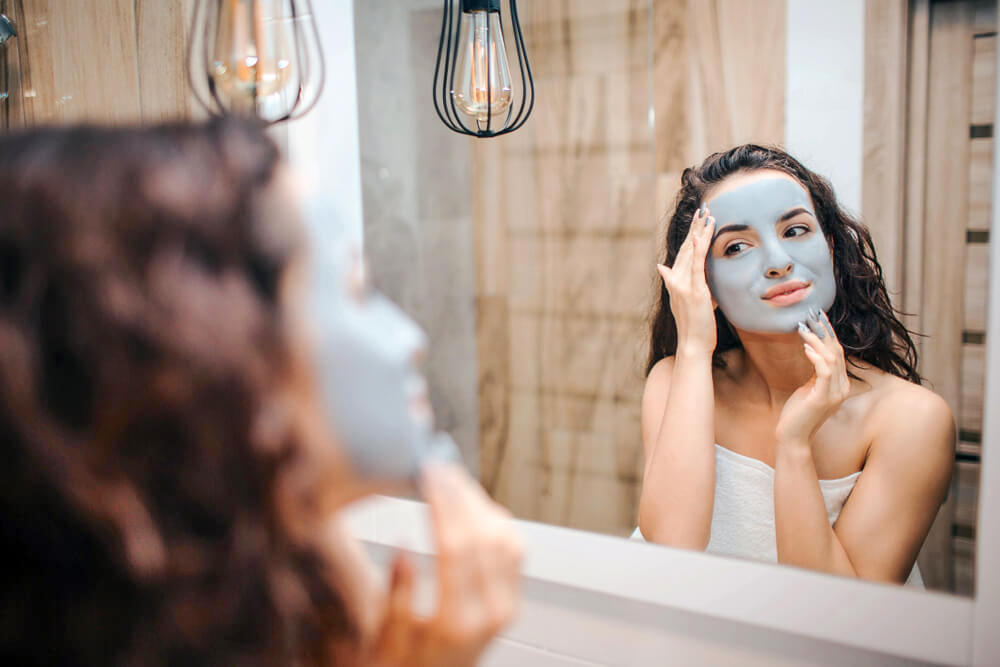 Woman applying clay mask on skin