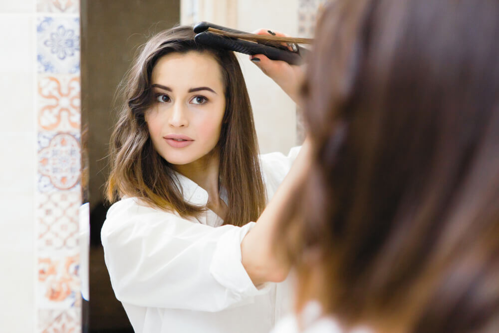 Woman curling hair with black flat iron