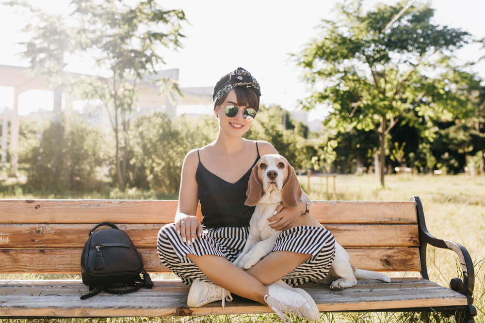 Woman on bench with dog, with bow around her hair