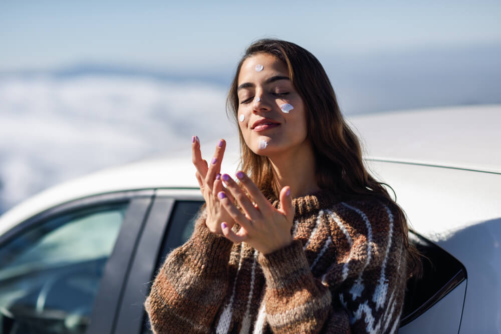 Woman applying sunscreen to face in winter