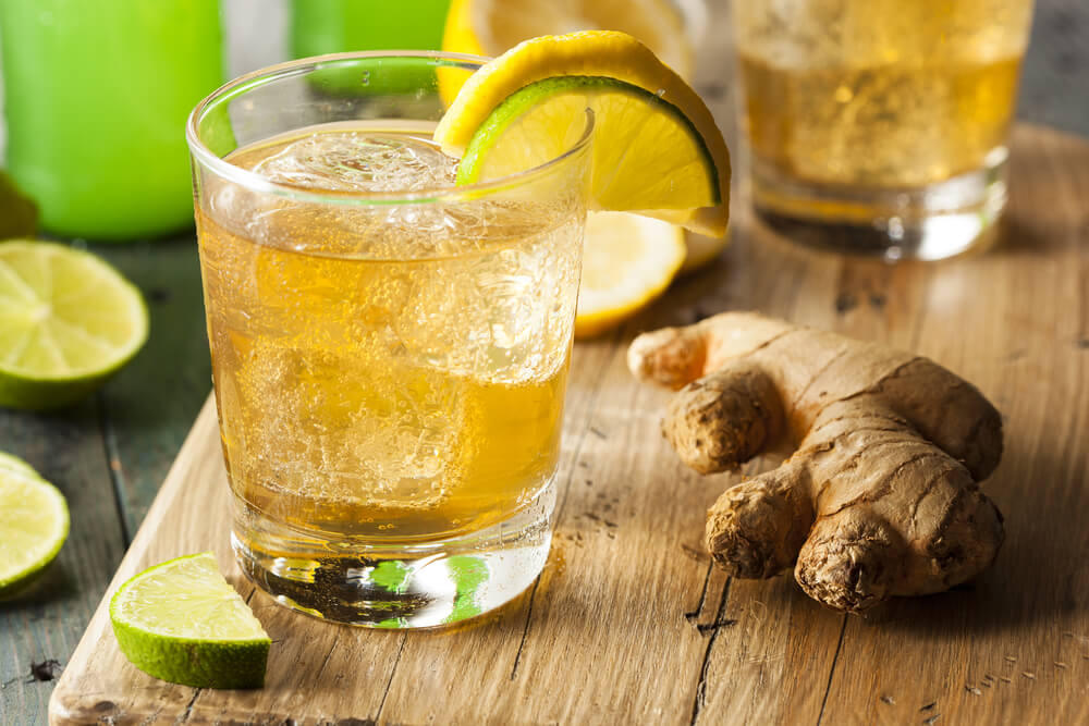 Glass of ginger beer with ginger root next to it