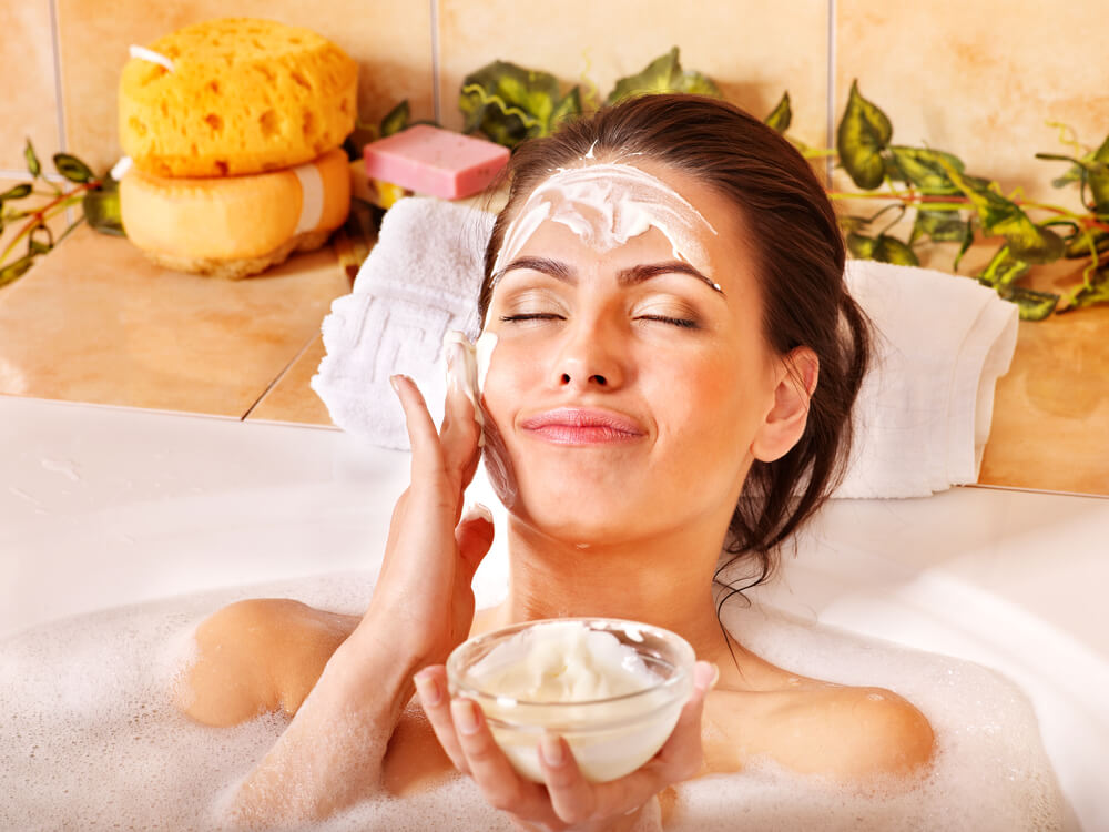 Woman applying face mask in bath