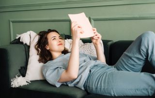woman reading celebrity memoir on sofa